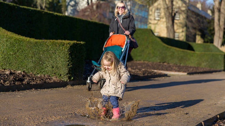 A little girl splashes in puddles at Wentworth Castle Gardens